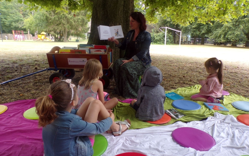 une bibliothécaire lit aux enfants à la plaine des sapins