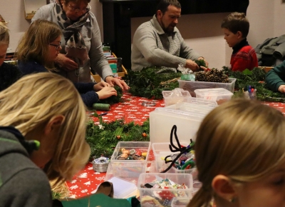 Des personnes autour d'une table réalisant une couronne de végétaux