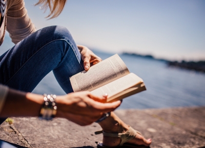 Femme lisant un livre sur un rocher au bord de la mer