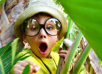 enfant étonné qui porte de grosses lunettes loupe et un chapeau de paille