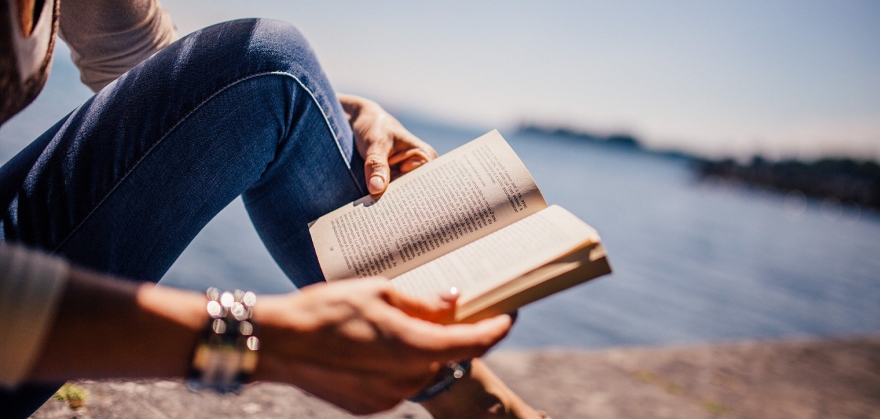 Femme lisant un livre sur un rocher au bord de la mer