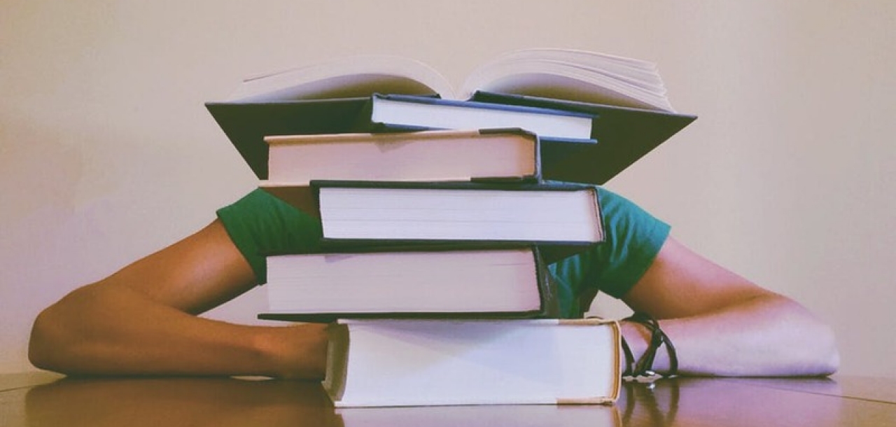 Gars écroulé sur son banc derrière une pile de livres