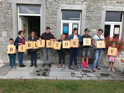 Photographie d'enfants portant des panneaux avec les lettres du mot bibliothèque devant la façade de la bibliothèque de Froichapelle