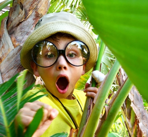 enfant étonné qui porte de grosses lunettes loupe et un chapeau de paille