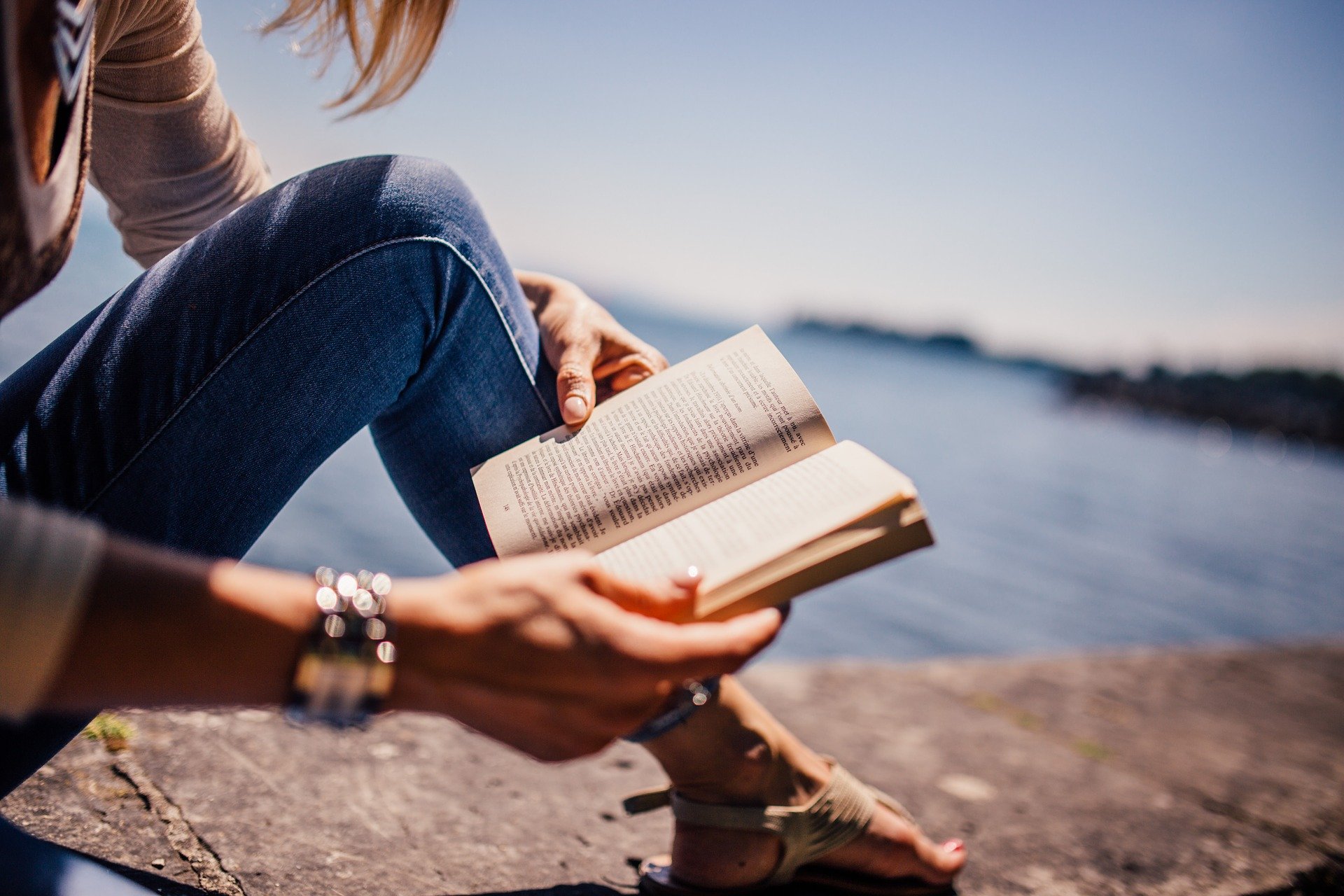 Femme lisant un livre sur un rocher au bord de la mer