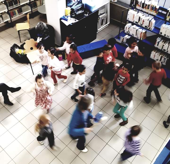 Enfants dansant au milieu d'une bibliothèque.