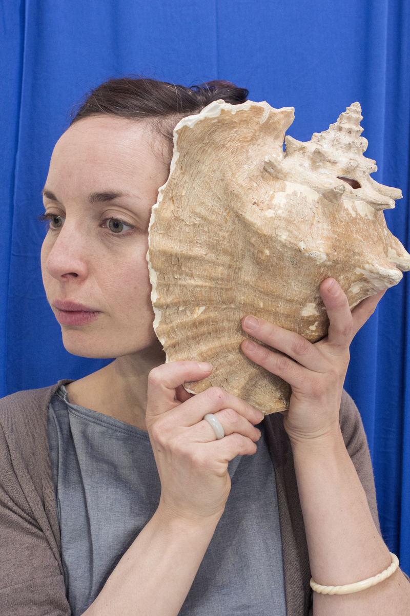 La comedienne écoutant un coquillage à l'oreille